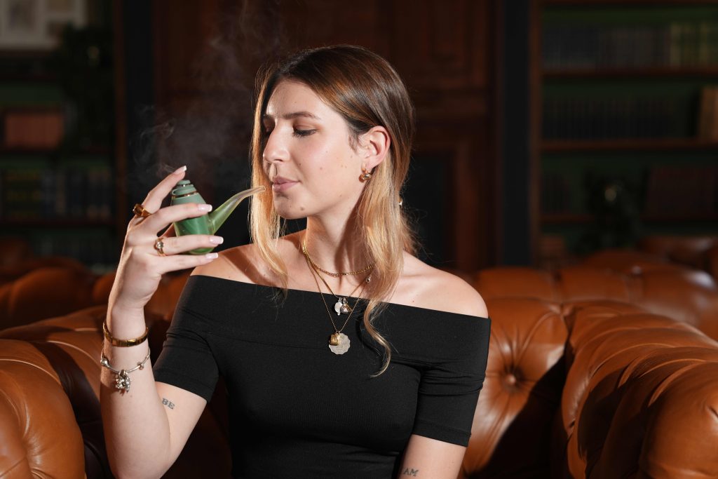 A beautiful woman enjoys Seknd Nature cannabis from a decorative pipe