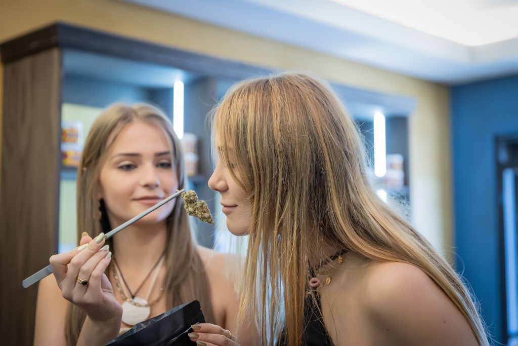 Two beautiful women sample the premium cannabis buds available exclusively at Seknd Nature